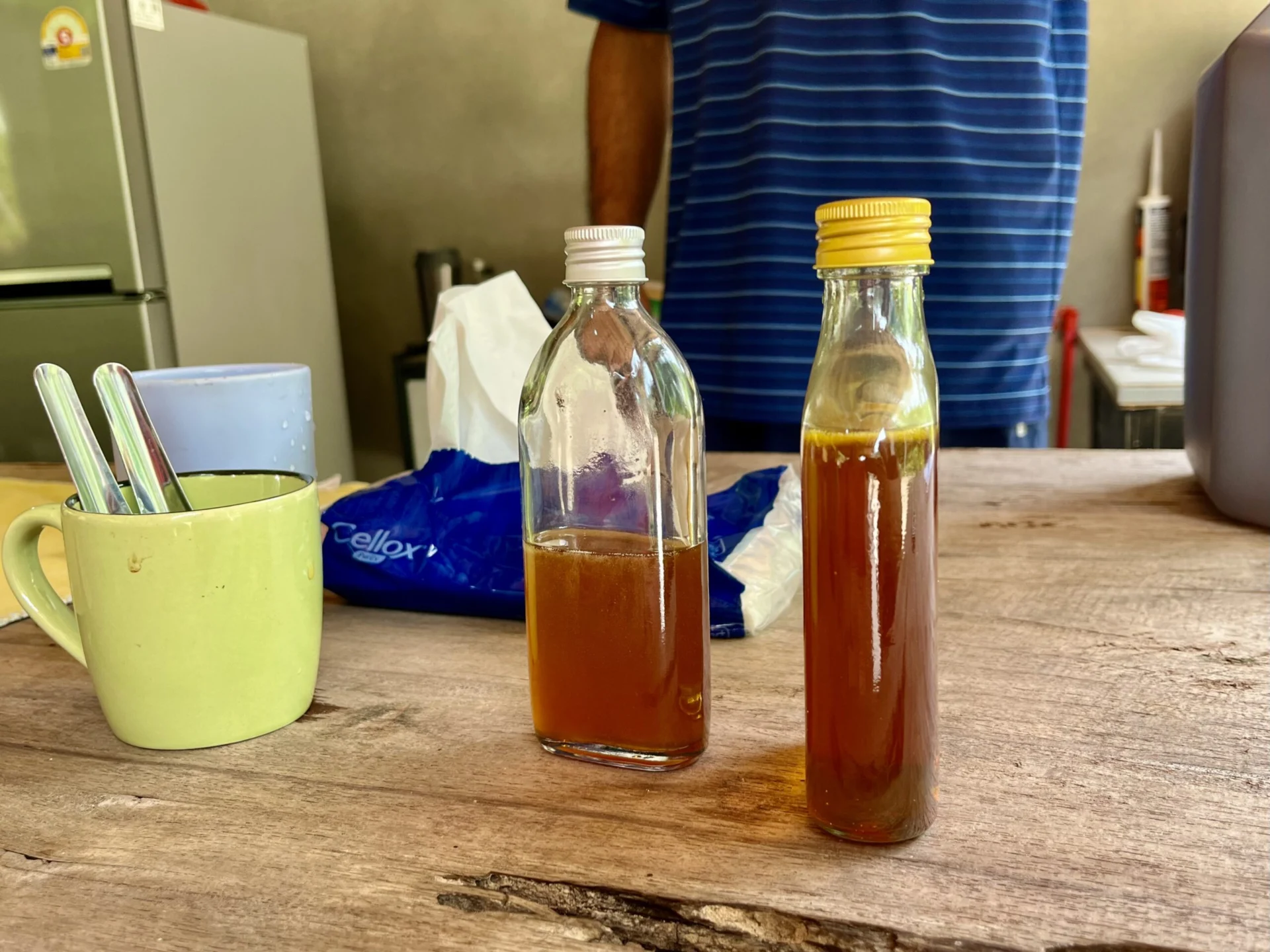 Two glass jars, partially filled with honey, sit on a wooden table.
